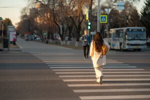 Foto de mulher atravessando faixa de pedestre caminhando, que é um exemplo de mobilidade ativa