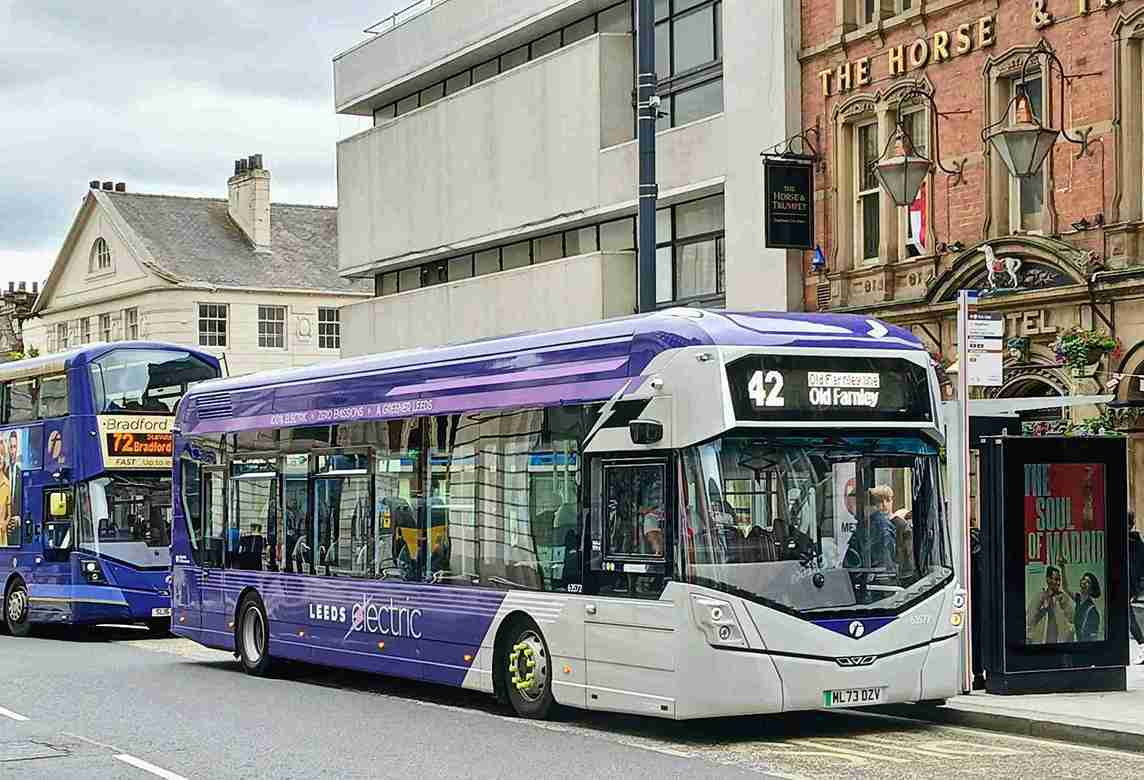 ônibus elétrico roxo em ponto de ônibus.