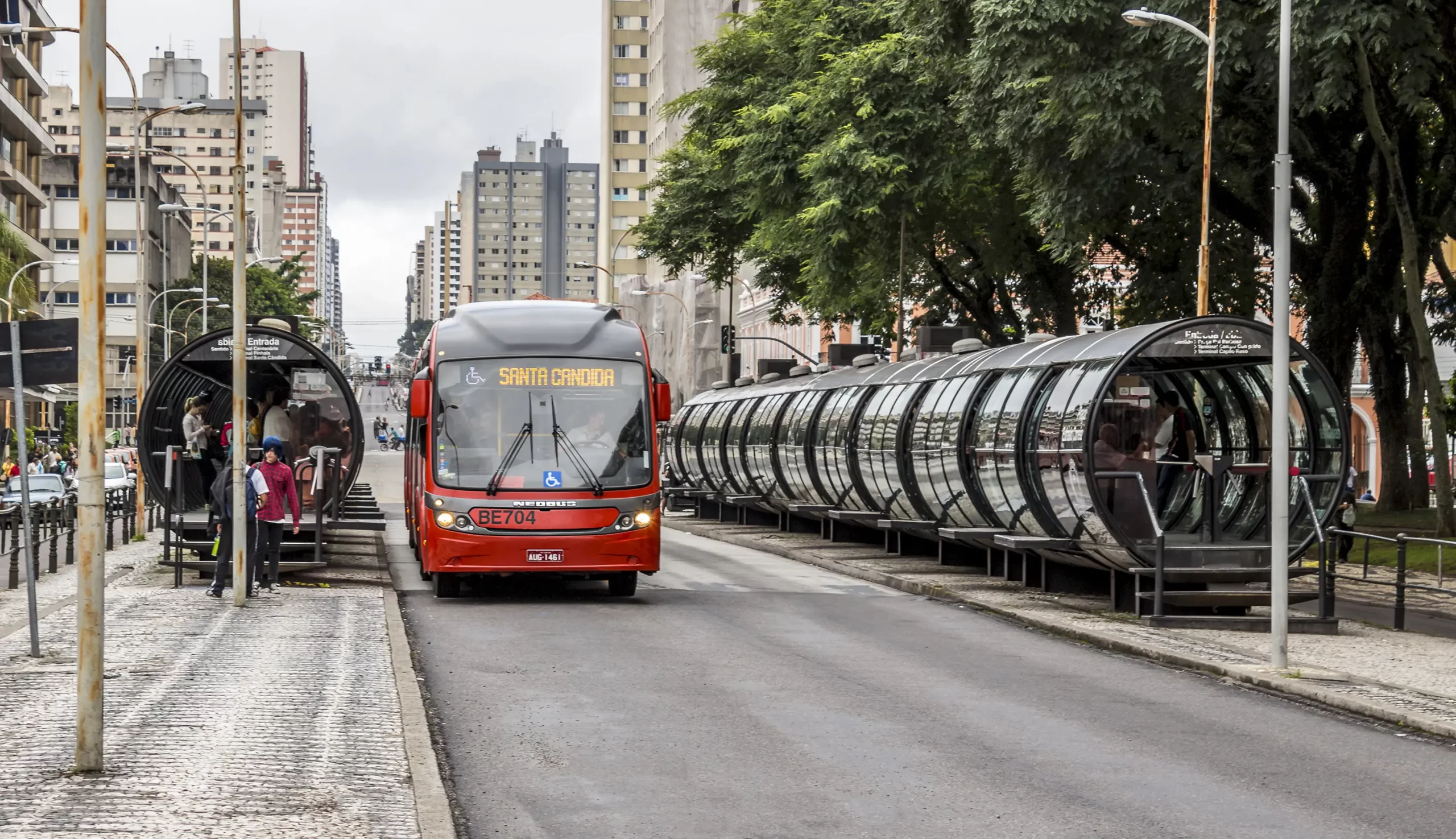 Foto de um ônibus biarticulado parado em estação tubo em Curitiba