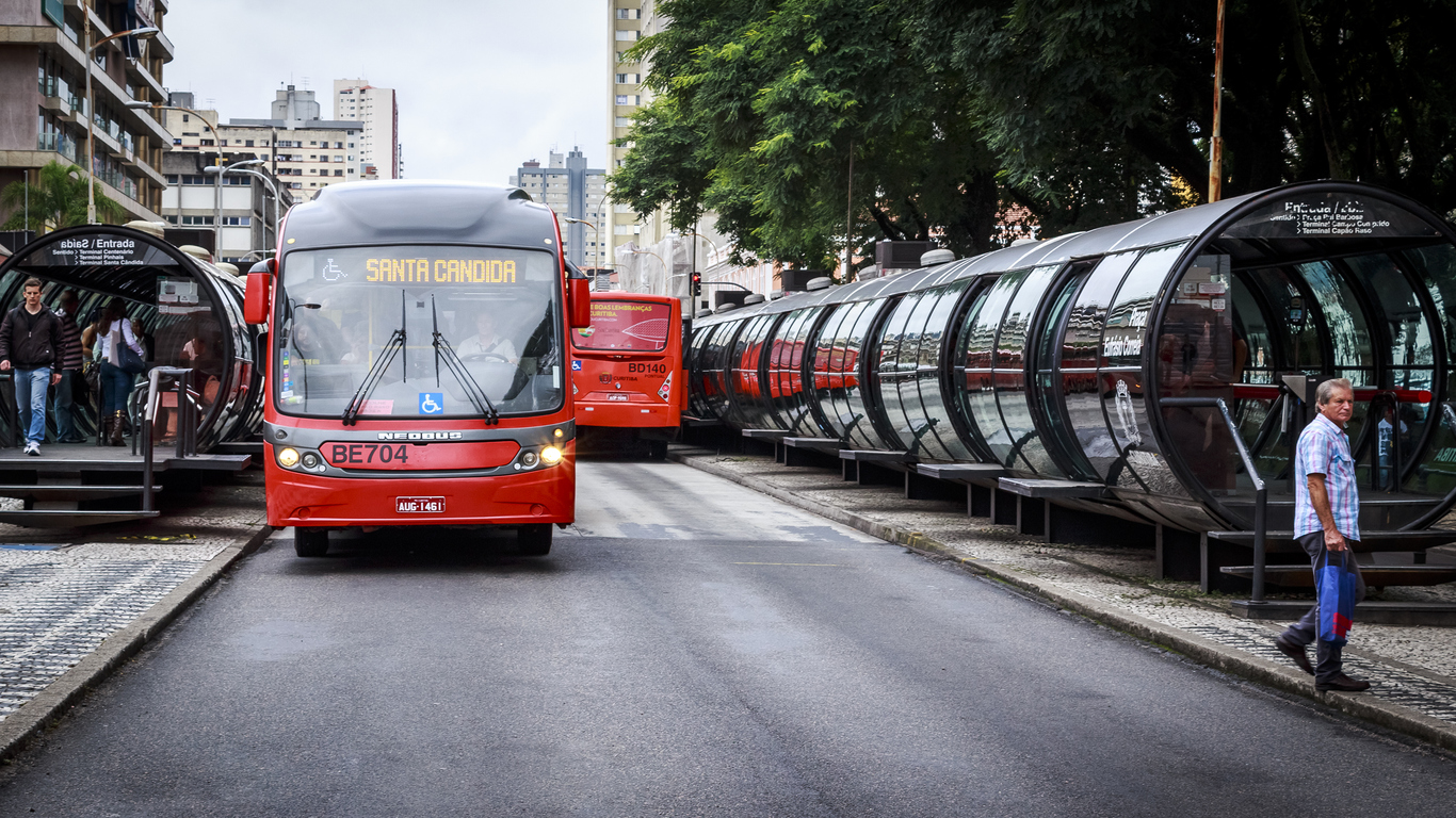 Foto de ônibus biarticulado parado em uma estação tubo de Curitiba.