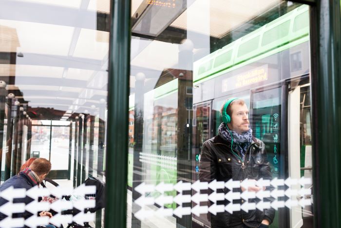 Foto de homem de fone de ouvido no ponto de ônibus.